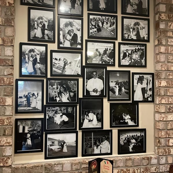 A wall of black and white framed wedding photos, some featuring couples and guests.