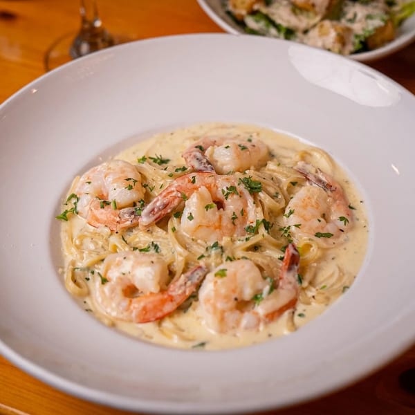 Creamy shrimp scampi pasta with parsley in a white bowl at Sal's Famous Pizzeria.