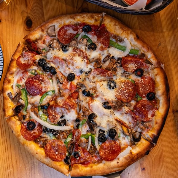 A whole Sal's Famous Pizzeria pizza, topped with pepperoni, olives, onions, and green peppers.