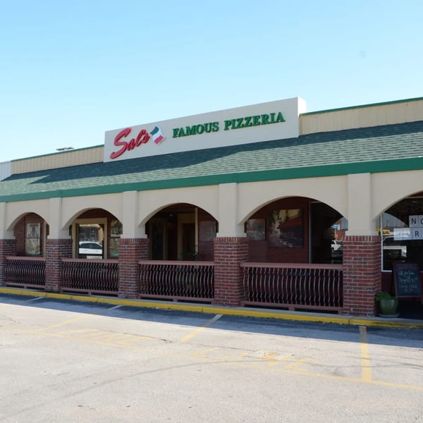 Exterior of Sal's Famous Pizzeria, a building with arched windows, brick accents, and a green roof.