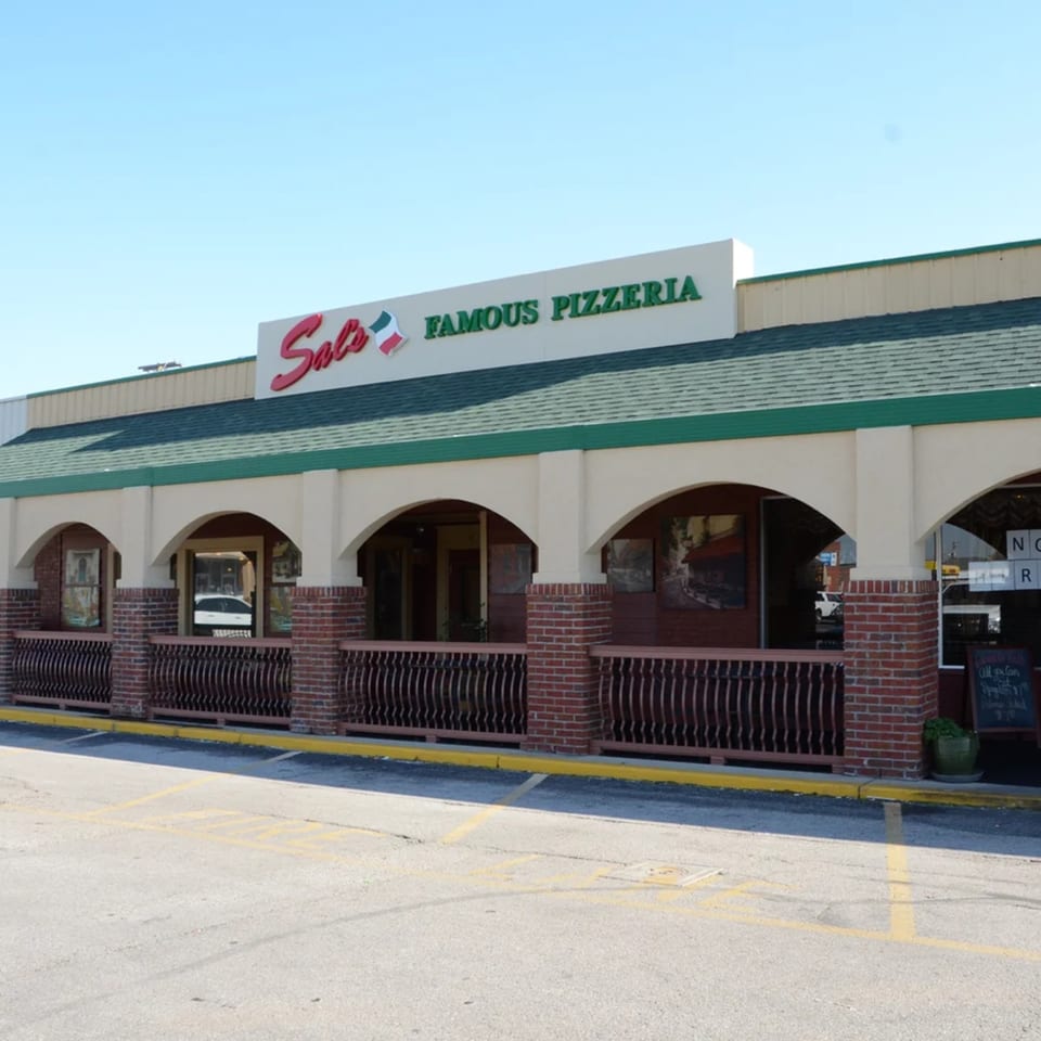 Exterior of Sal's Famous Pizzeria, a building with arched windows, brick accents, and a green roof.