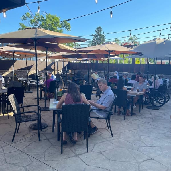 Patrons enjoying outdoor dining under large umbrellas on a sunny day at Sal's Famous Pizzeria.
